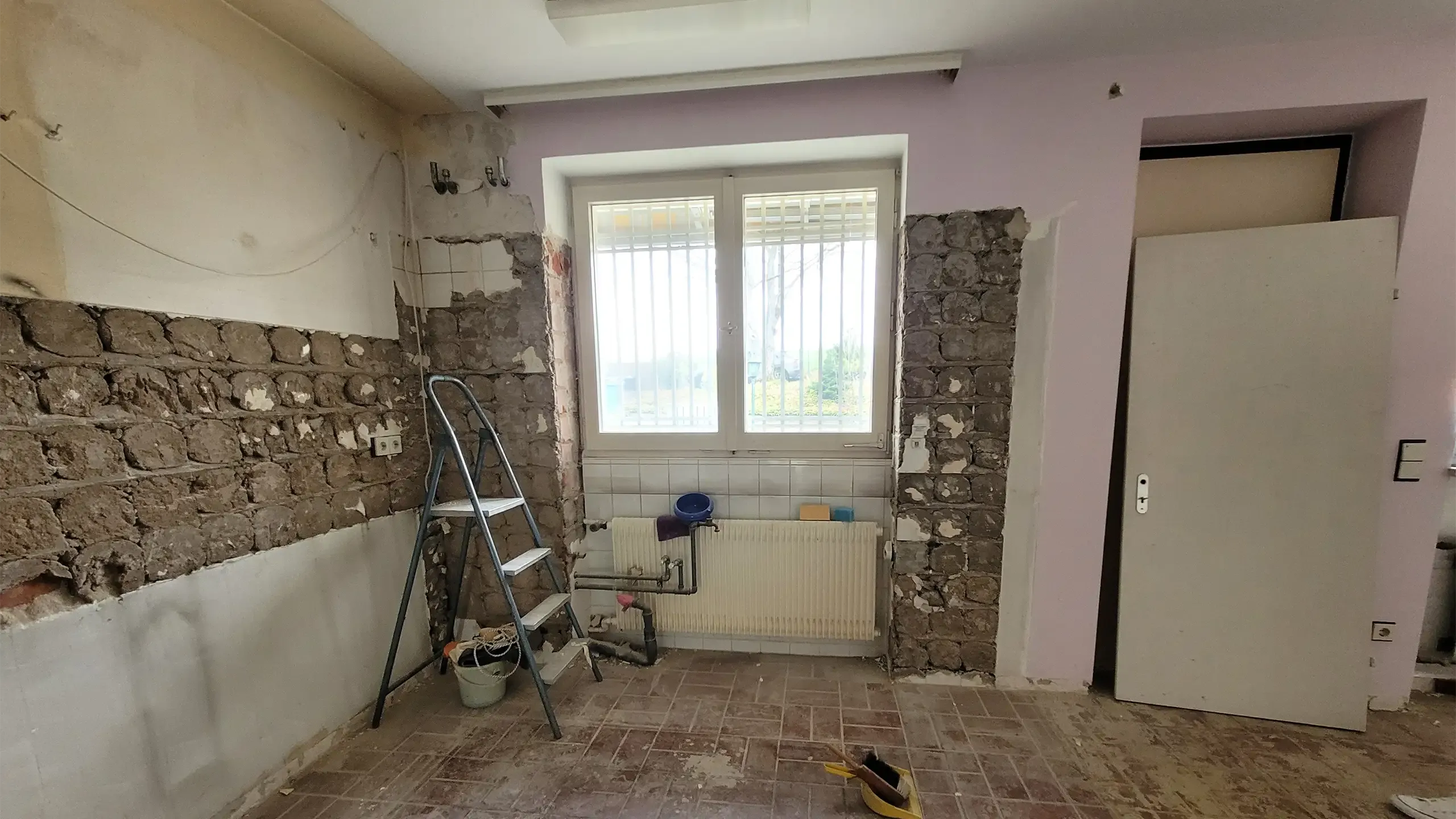 Vorher-Aufnahme: entkernter Altbau-Raum mit freigelegtem Bruchsteinmauerwerk und Bauschutt.