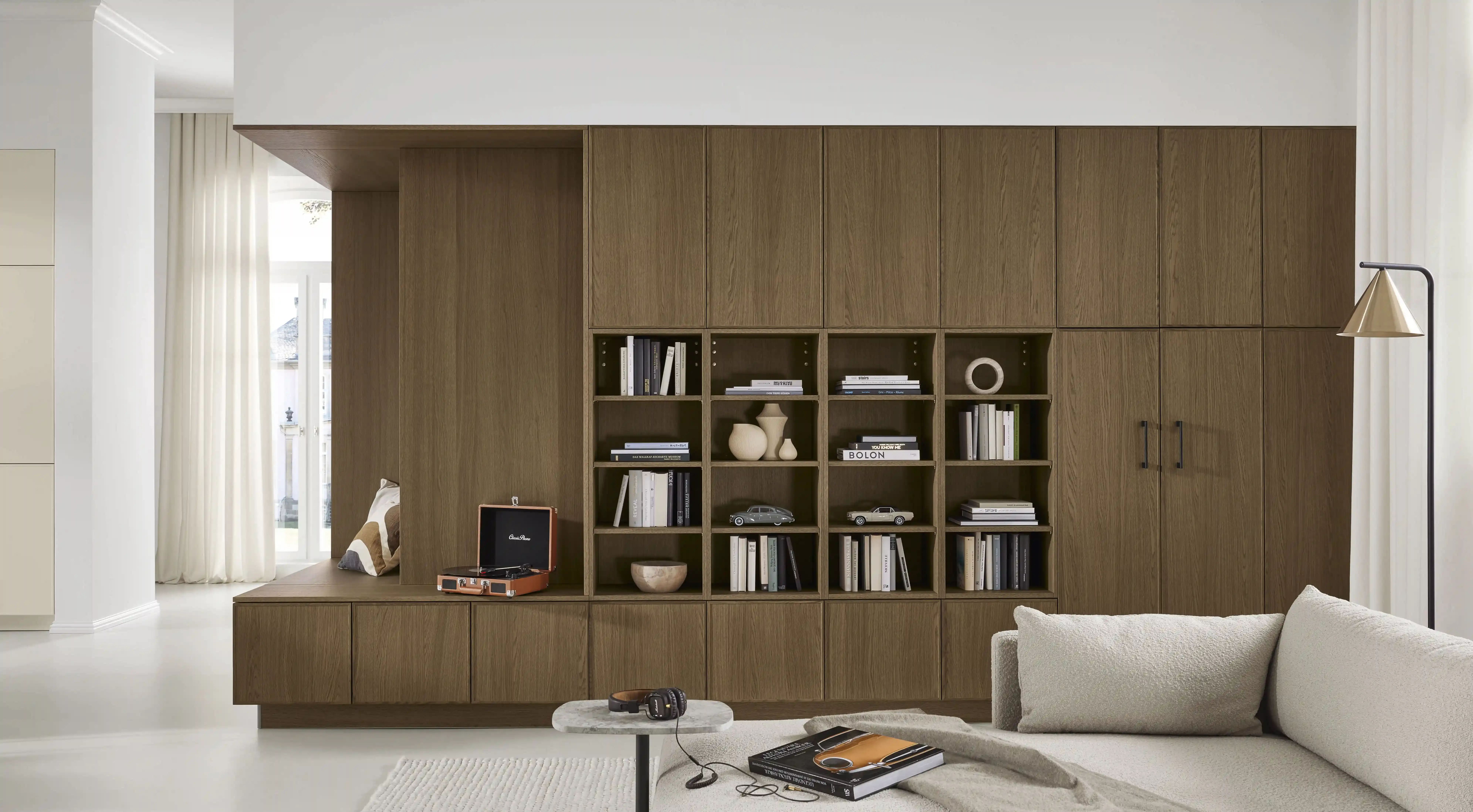 Wohnwand in Nussbaum mit Bibliotheksregal, eingebetteter Sitzbank-Nische und Sideboard mit Plattenspieler