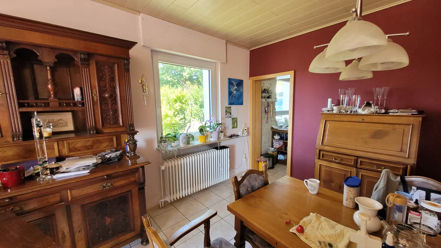 Vorher-Zustand: Esszimmer mit Vintage-Vitrinen, Massivholz-Esstisch und dunkelroter Wandfarbe.