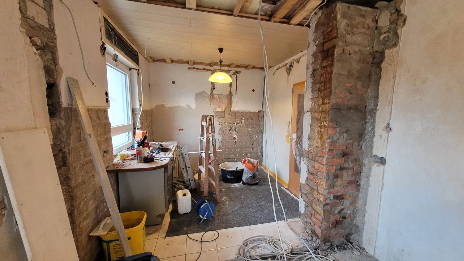 Vorher-Aufnahme: Altbau-Sanierung mit freigelegter Bruchsteinwand und sichtbarem Holzbalken-Dach.