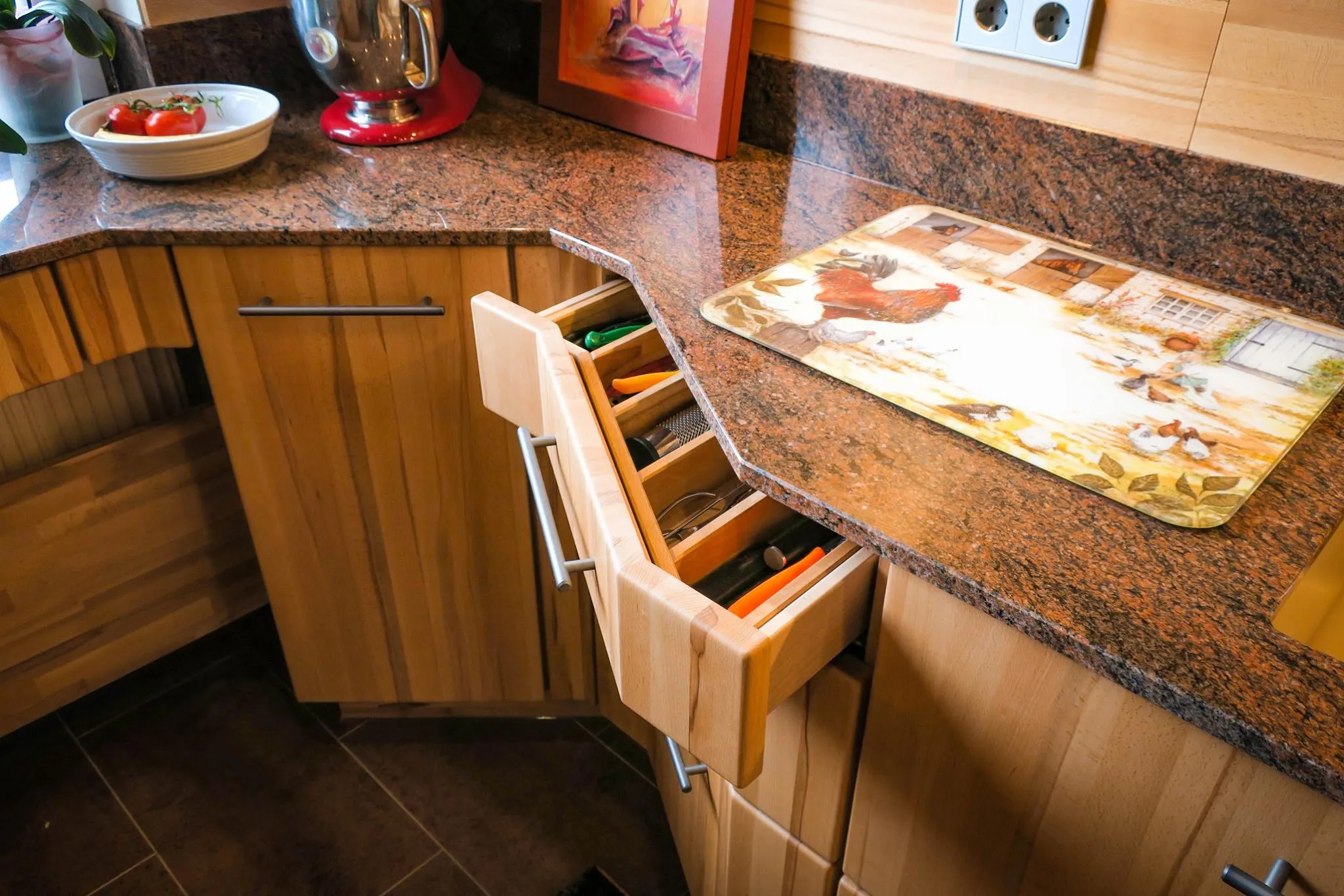 Detail eines ausgezogenen Eckschrank-Innenausstattung mit Besteckeinsatz und Geschirreinteilung, darüber Granit-Arbeitsplatte und Eichen-Front