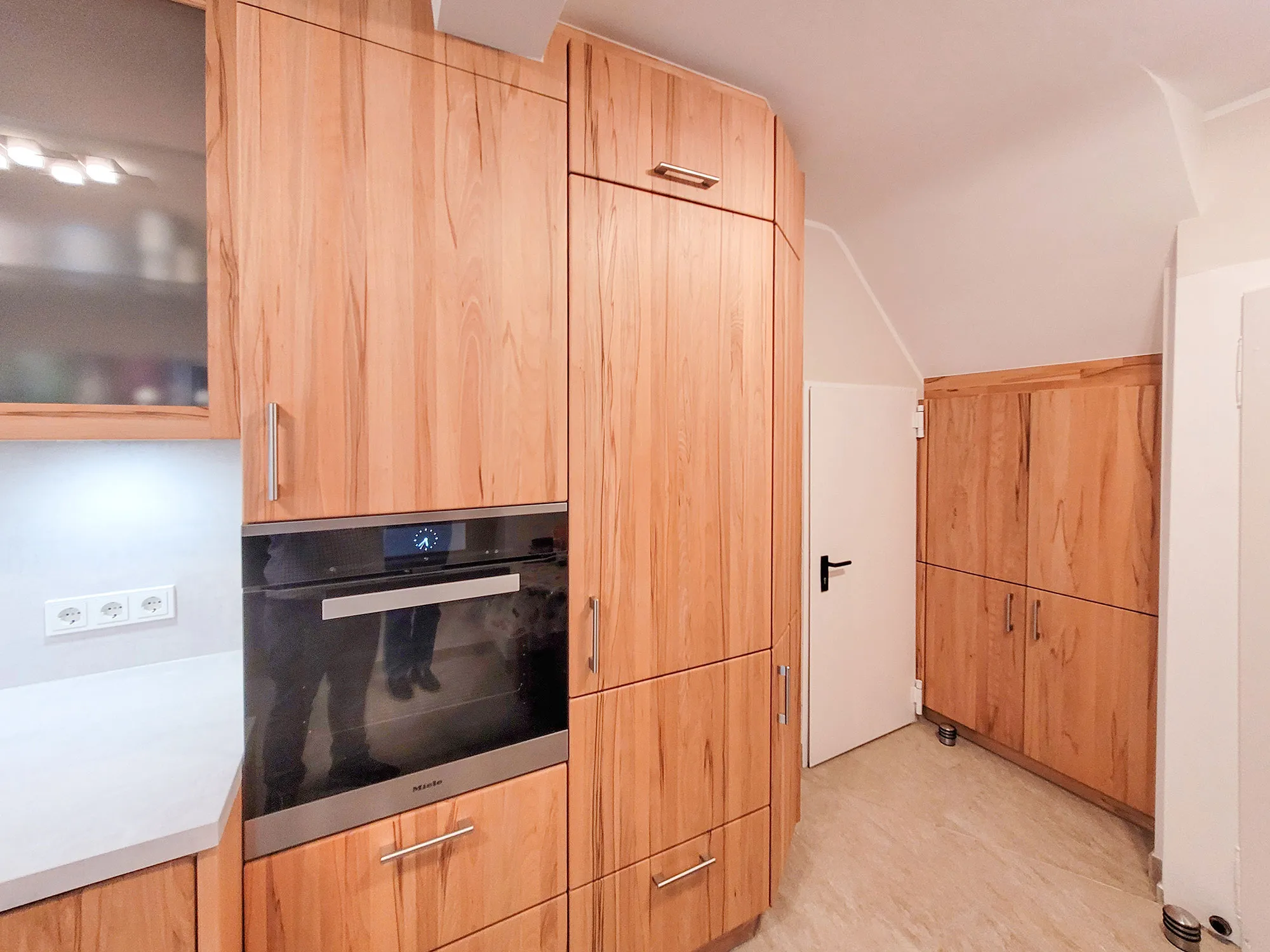 Massivholz-Hochschrankzeile mit integriertem Backofen unter einer Dachschräge.