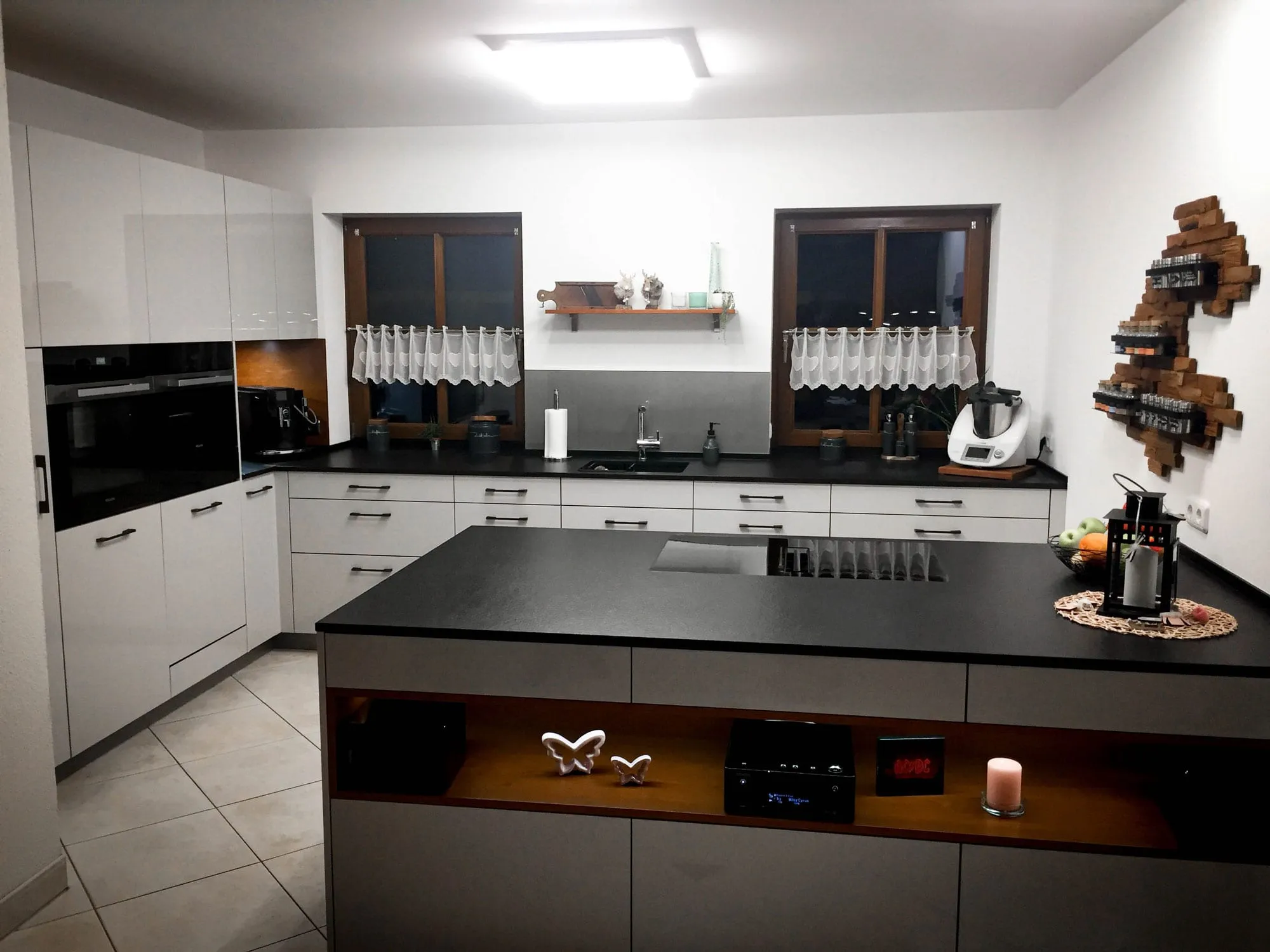 U-Küche mit Insel und beleuchteter Holznische, Hochglanzfronten in Creme und dunkler Arbeitsplatte