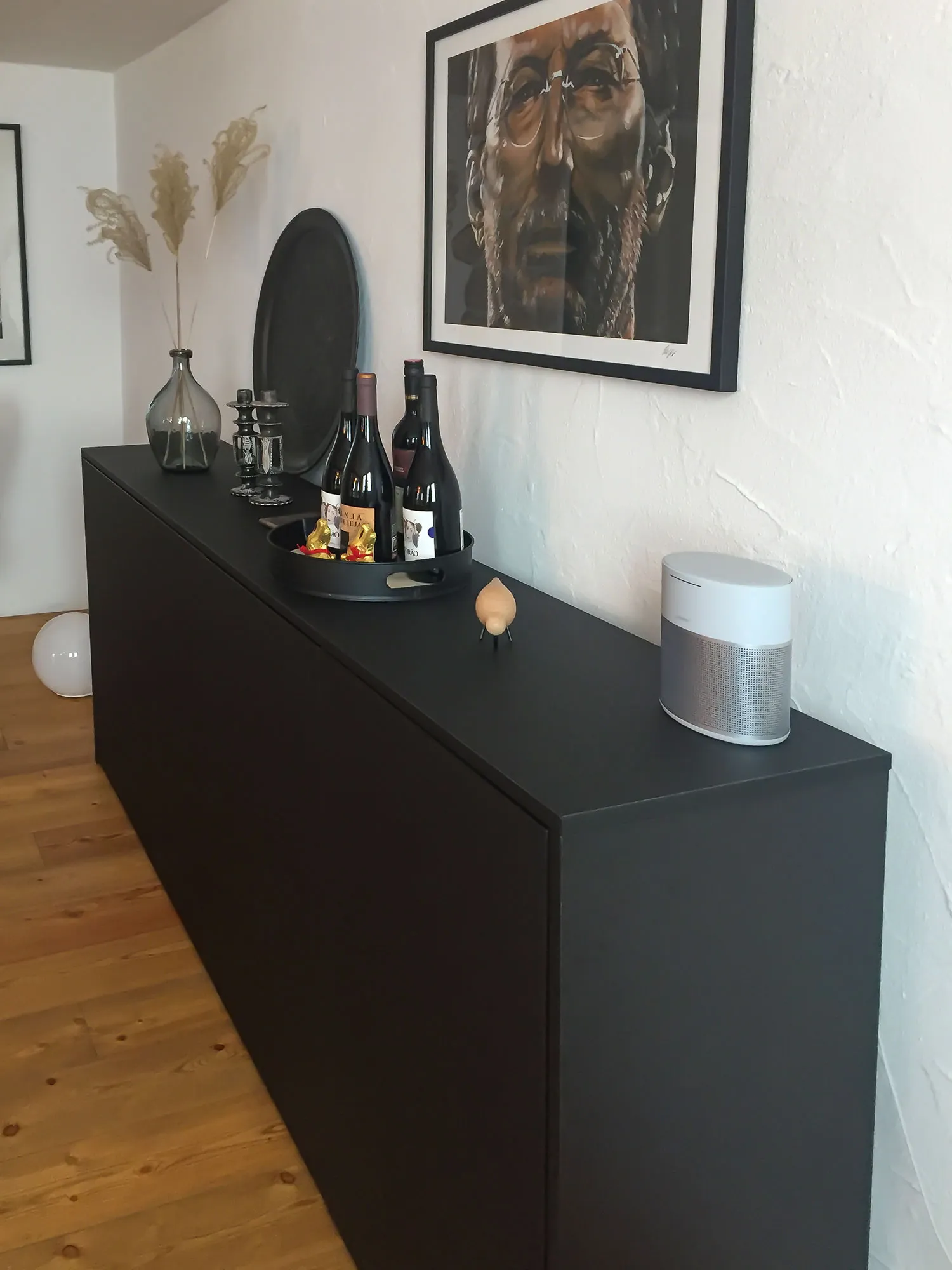 Schwarzes Sideboard mit Weinflaschen-Tablett, Trockenblumen-Vase und Bluetooth-Lautsprecher