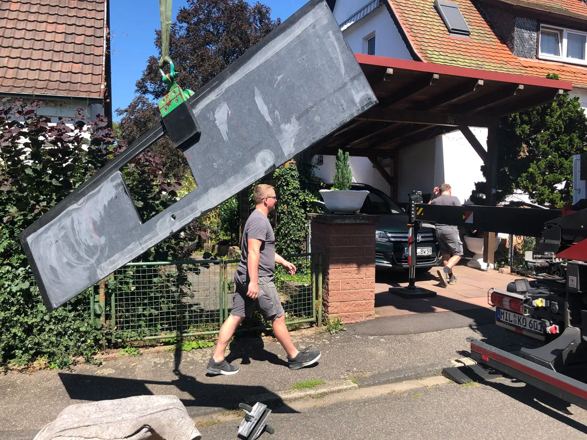 Anlieferung einer großen Steinarbeitsplatte per Kran und Monteur