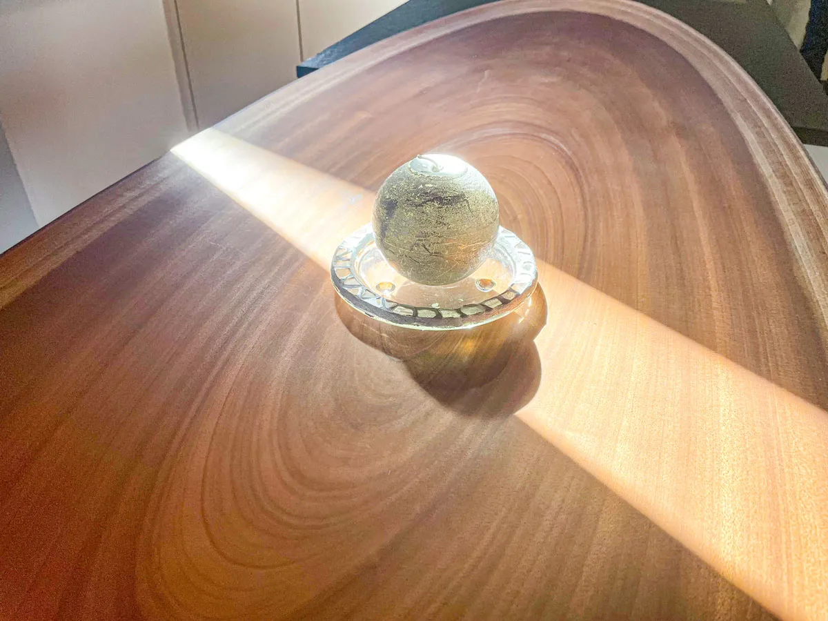 Detail einer runden Massivholz-Tischplatte mit Glaskugel-Deko