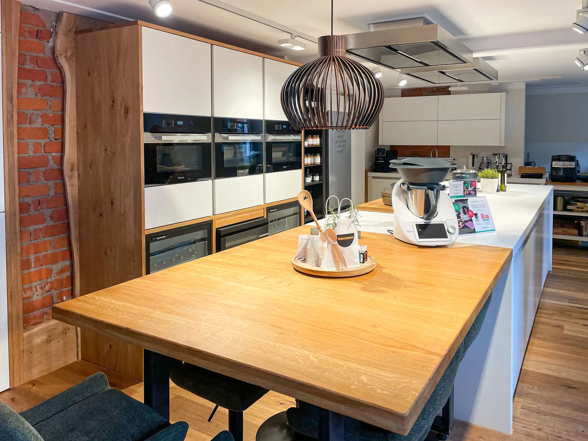 Holz-Esstheke mit Thermomix, Korb-Pendelleuchte und Backsteinwand im Hintergrund