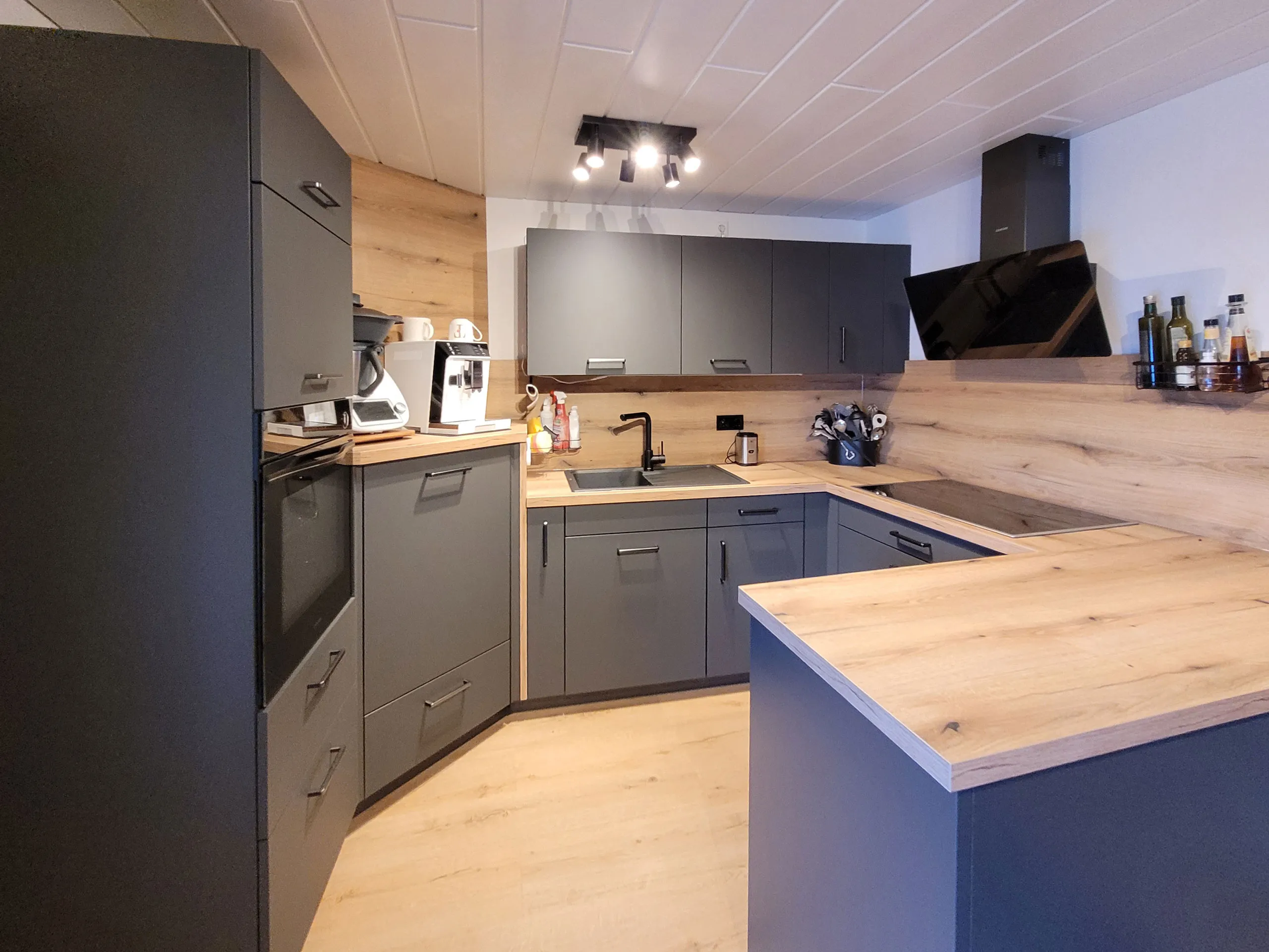 U-Form-Küche in Graphit und Eiche mit Halbinsel und Arbeitsplatte in Holzoptik, Kundenprojekt