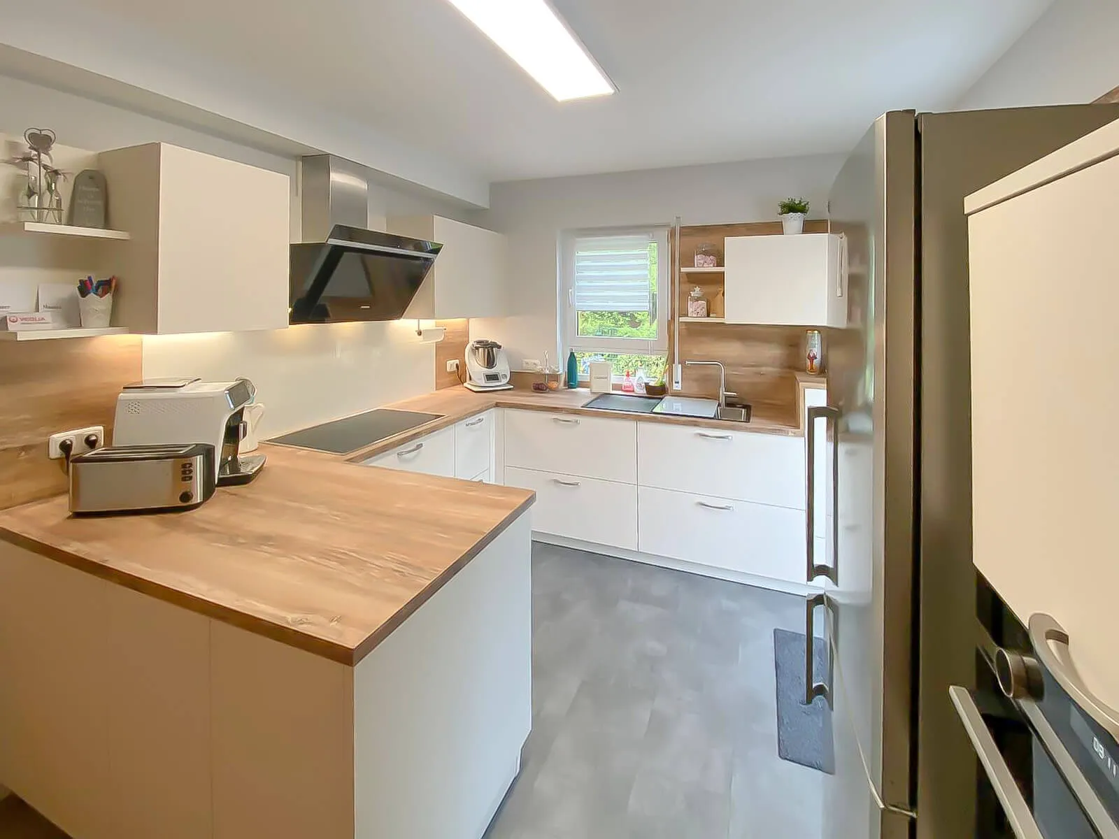 U-Küche mit Eichenholz-Arbeitsplatte, Halbinsel, Spüle am Fenster und Side-by-Side-Kühlschrank