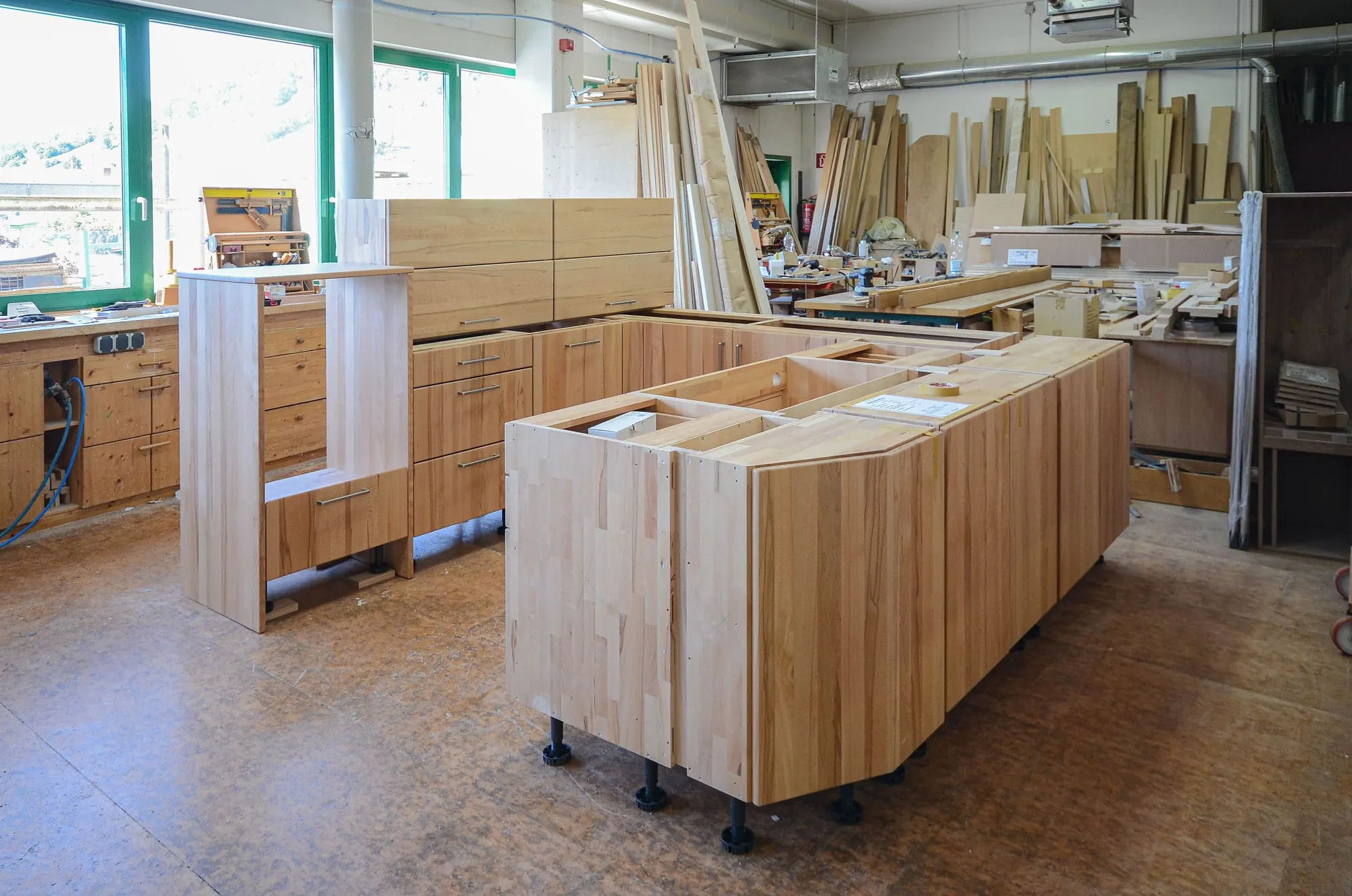 Werkstatt-Aufnahme der Massivholz-Kochinsel im Probeaufbau mit sichtbaren höhenverstellbaren Füßen.