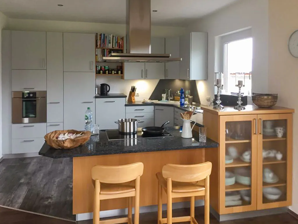 Klassische Wohnküche mit Holz-Insel, Granitarbeitsplatte, Barhockern und Vitrinen-Hochschrank