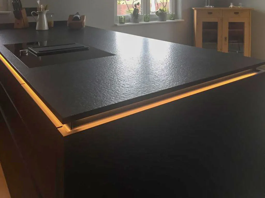 Schwarze strukturierte Arbeitsplatte mit warmer indirekter LED-Unterbeleuchtung