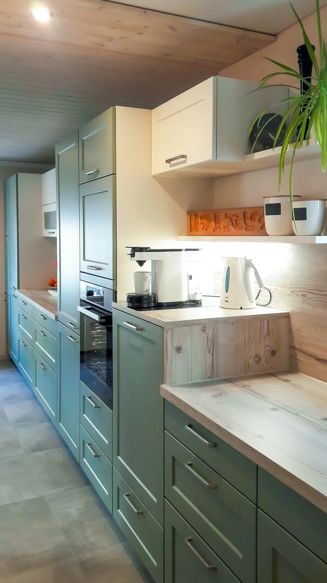 Grüne Hochschrankzeile mit Backofen, Holz-Sideboard und Pflanzen-Deko