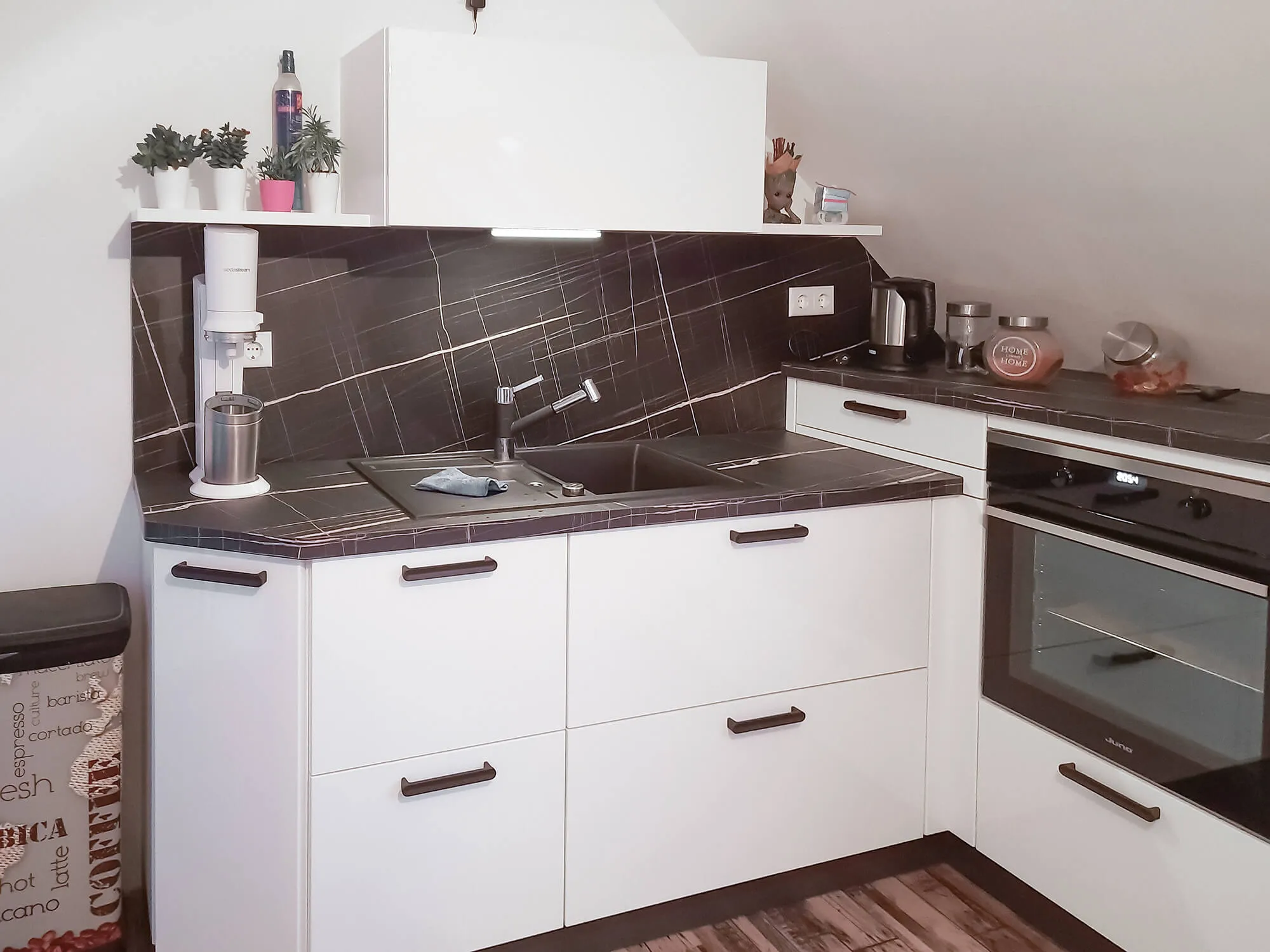 L-Eck-Küche mit Spüle, Backofen, Marmor-Arbeitsplatte und Eckregal mit Pflanzen-Deko