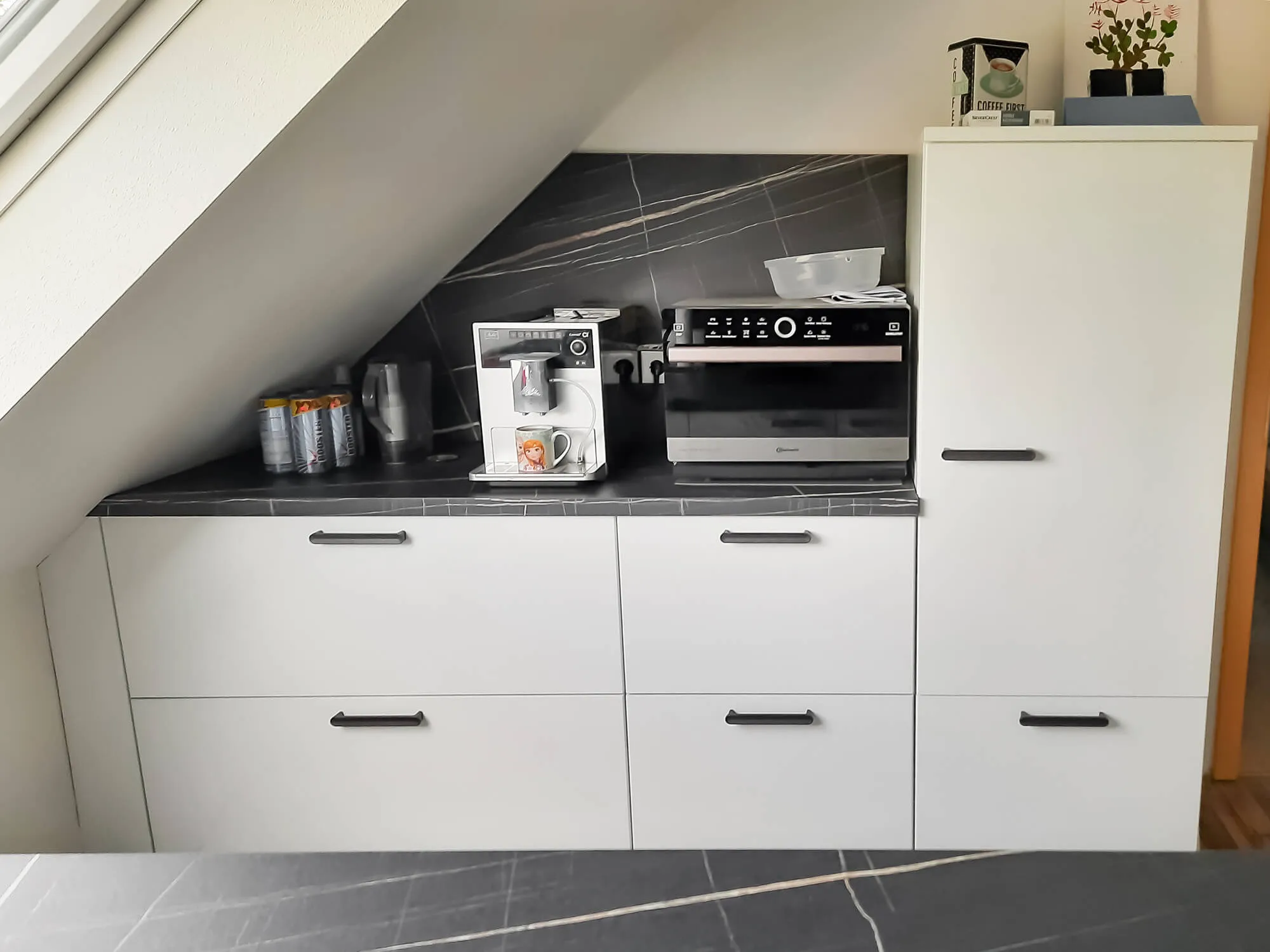 Weiße Küchenzeile mit Marmor-Arbeitsplatte, schwarzen Griffen und Espressomaschine
