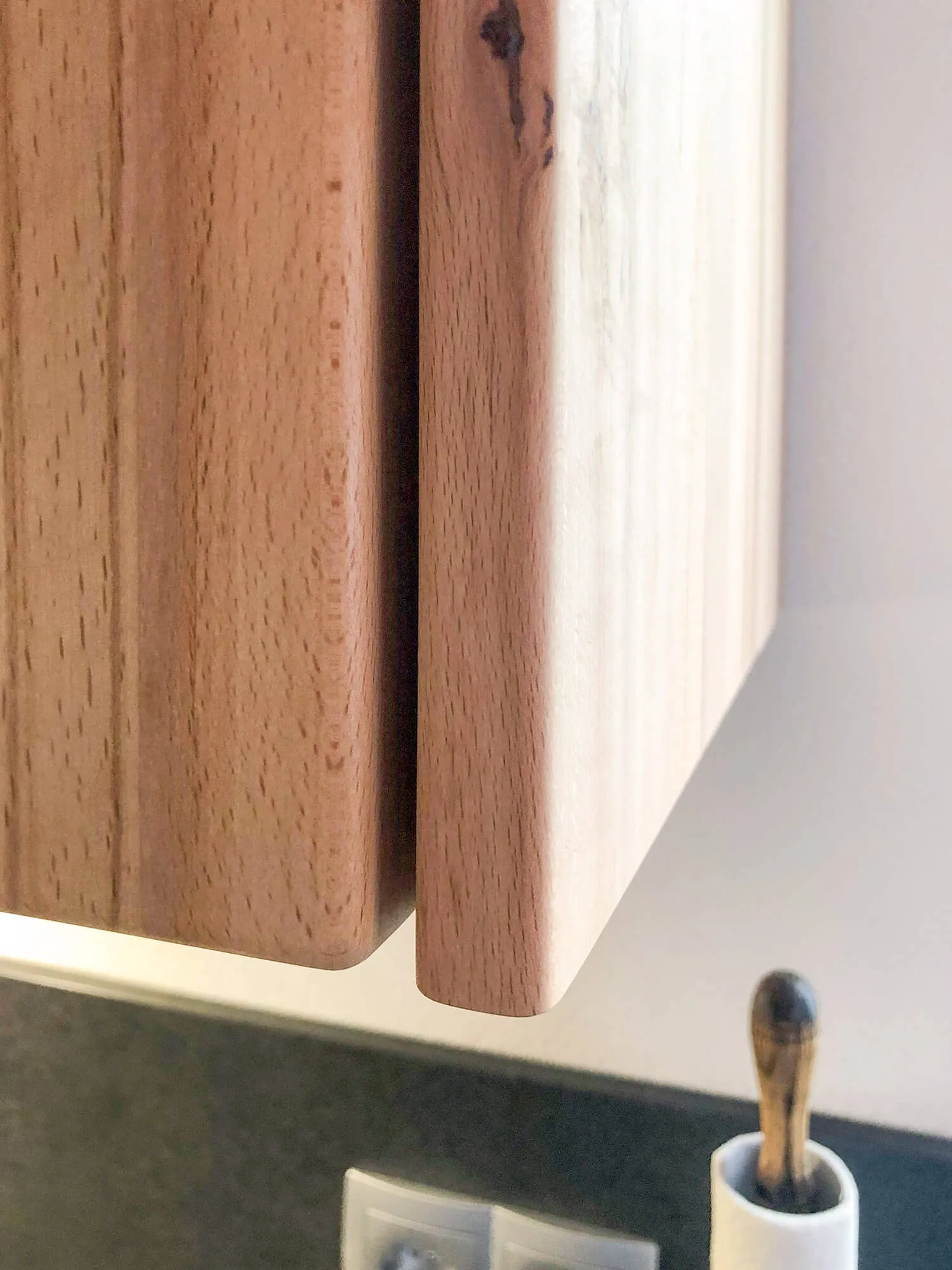 Detailaufnahme massiver Holzschneidebretter und Keramikbecher mit Holzlöffel in Küche