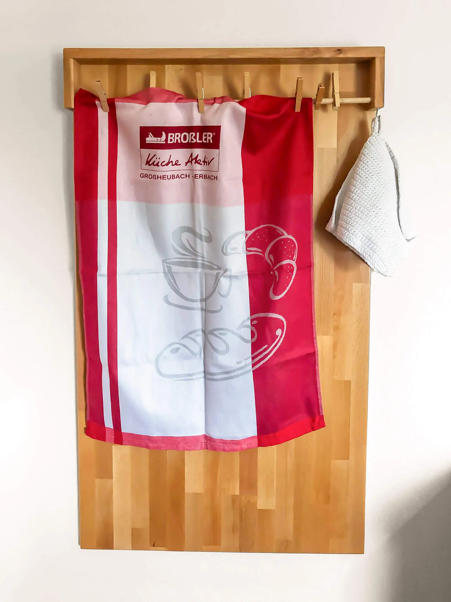 Geschirrtuch und Topflappen mit Broßler-Logo an Holzhakenleiste – Küchen-Accessoire bei Broßler Küche Aktiv