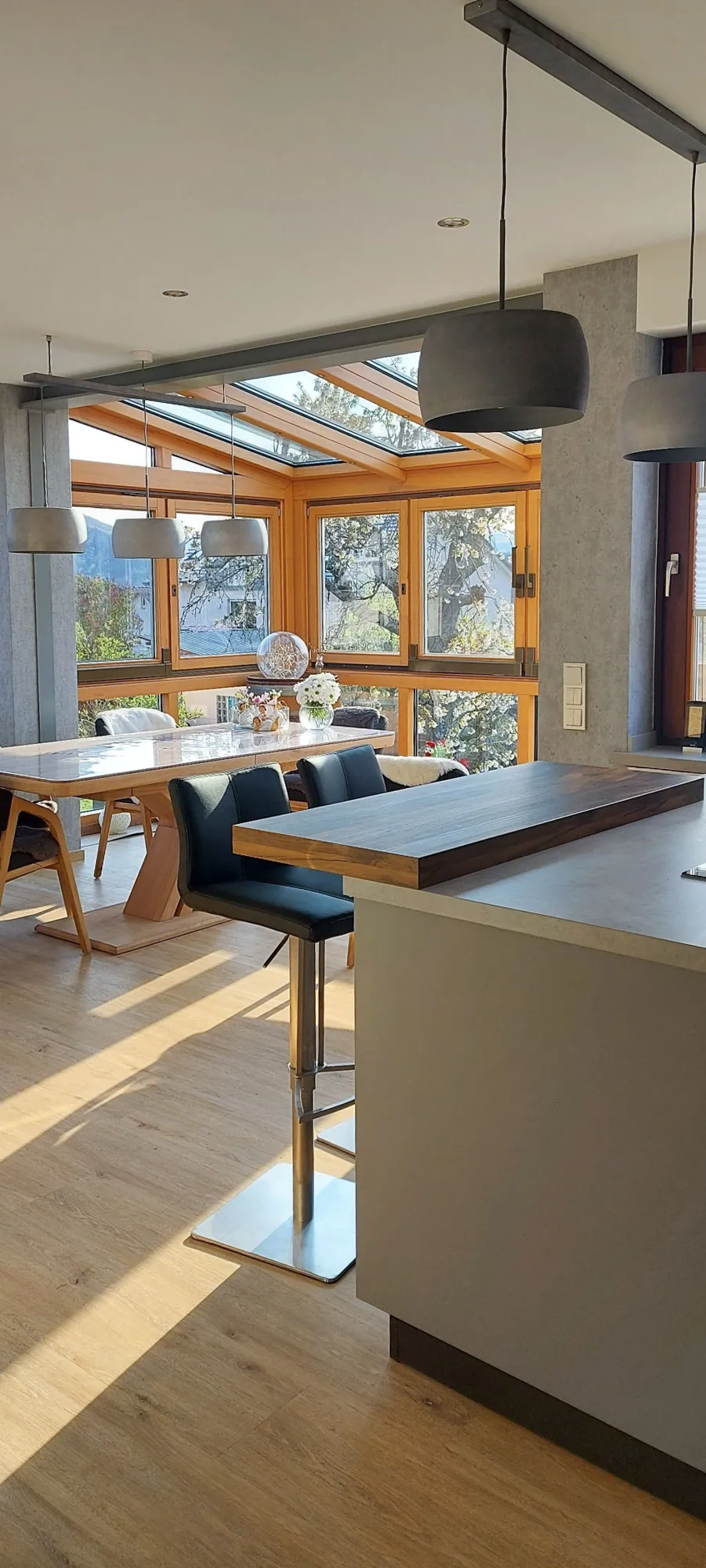 Blick aus der Küche in den Wintergarten-Essbereich mit Holz-Esstheke und Barhockern